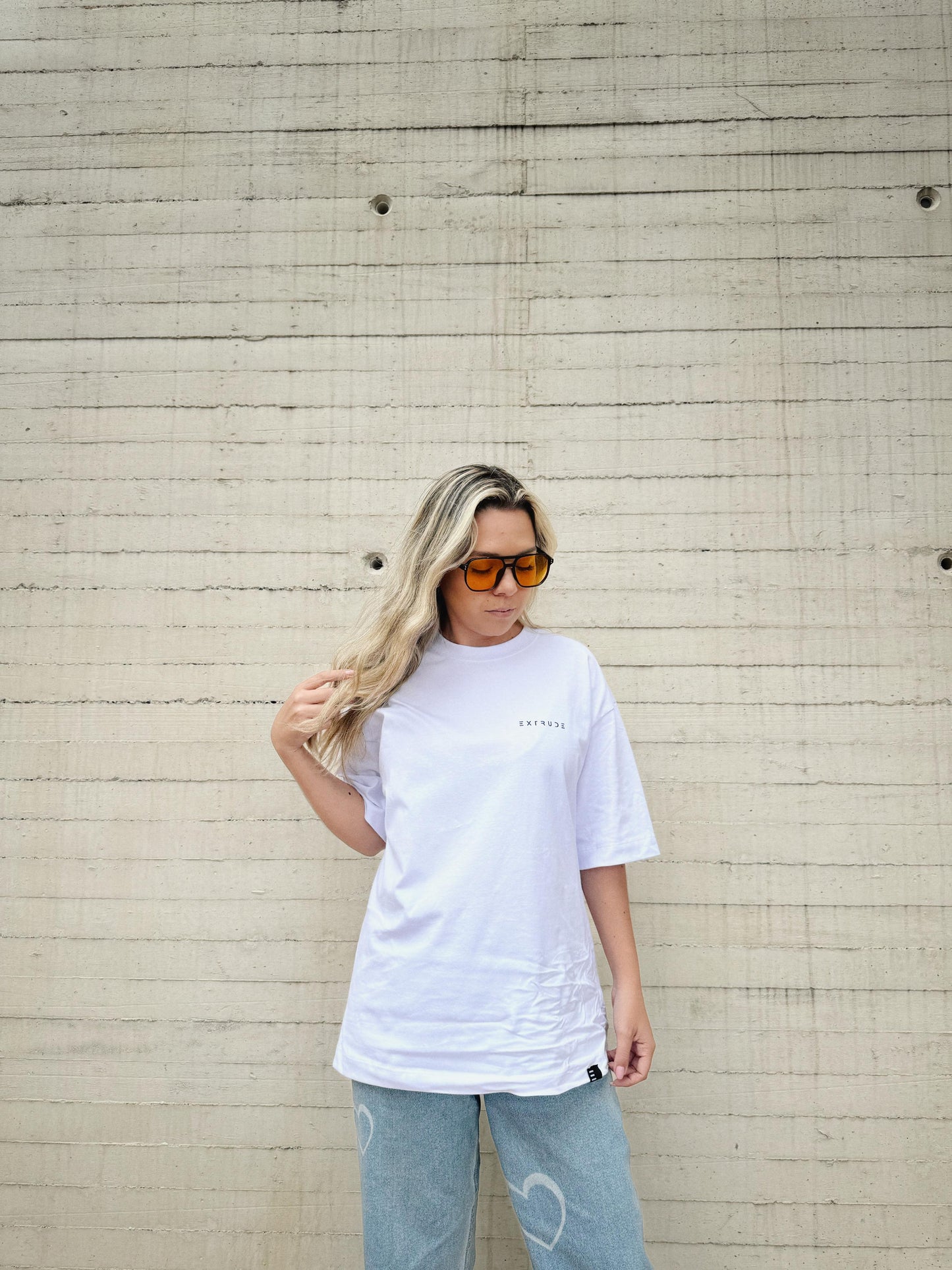 Camiseta oversize blanca Extrude Less is More para mujer con logo minimalista en el pecho – streetwear inspirado en arquitectura, moda urbana Colombia